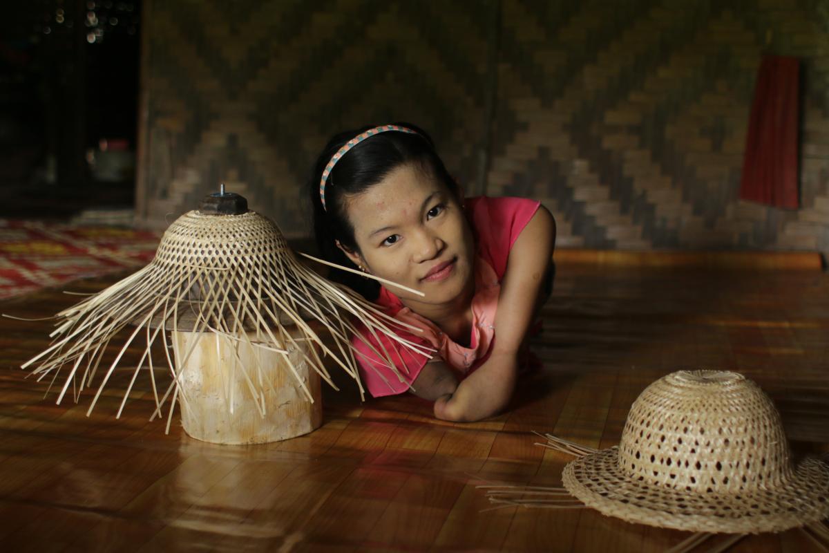Zin Mar Aye from Ye Kyi Township (Ayeyawady Region, Myanmar), who has a congenital condition, is shown here making bamboo hats which are sold in the market.