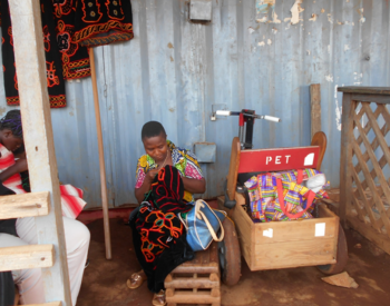 Picture of Nina in front of her shop, embroidering a dress for a customer, copyright Cameroon Baptist Convention Health Services in Cameroon